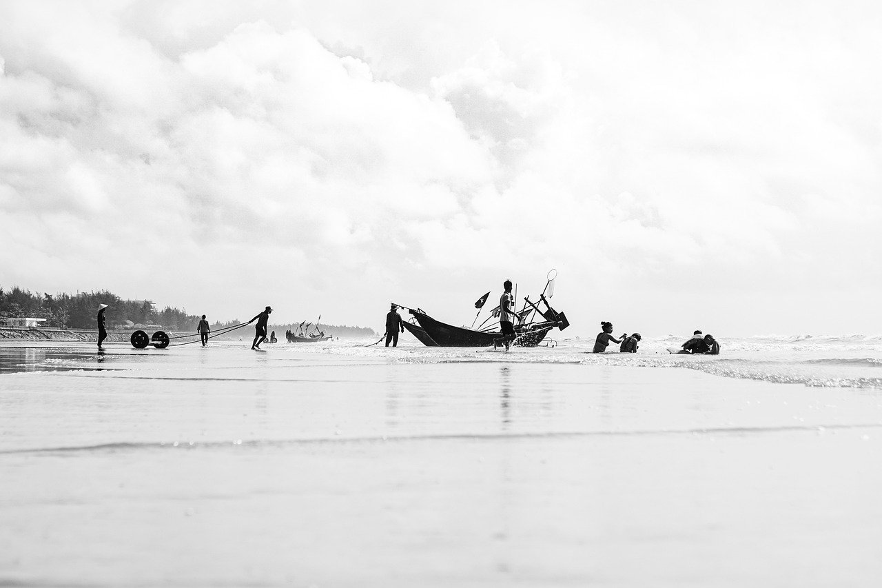 Picture of people pulling a boat on the beach.